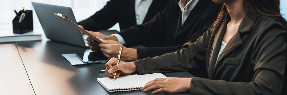 People in business attire taking notes at a conference table.