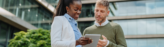 man and woman looking at tablet outside of hospital